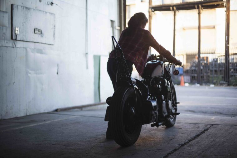 車庫からバイクを出す女性